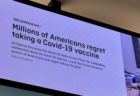 オーストラリアの空港のスクリーンで「アメリカ人の約4分の1がワクチン接種を後悔している」と報じた新聞記事が表示される