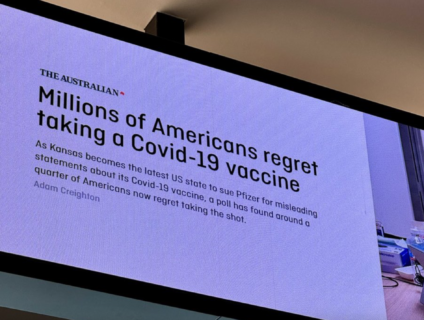 オーストラリアの空港のスクリーンで「アメリカ人の約4分の1がワクチン接種を後悔している」と報じた新聞記事が表示される